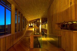A modern interior with wooden paneling, a glass railing, and a staircase leading to an upper level. - Tierra Patagonia, Beckons (Torres del Paine)