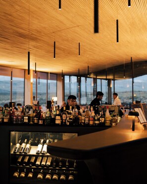 A bar area with a wooden ceiling and large windows.