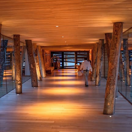 A corridor with wooden beams, glass walls, and a wooden floor.