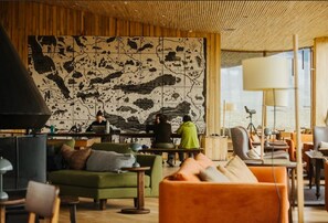 A modern interior with a large wall mural, wooden ceiling, and cozy seating areas.