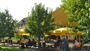 Ein Straßencafé mit gelben Sonnenschirmen, Korbtischen und -stühlen.