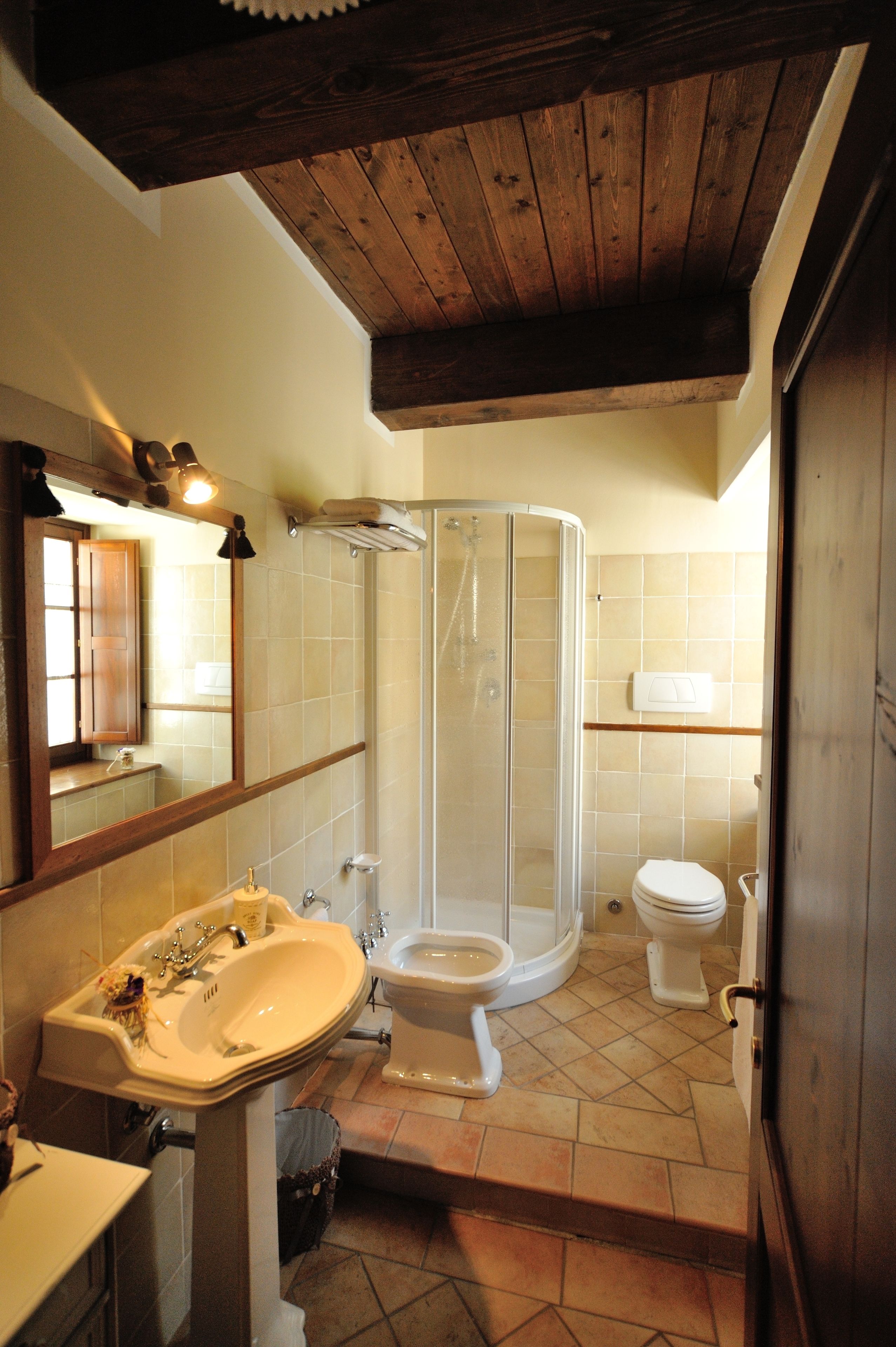 A bathroom with a shower, sink, toilet, and a mirror.