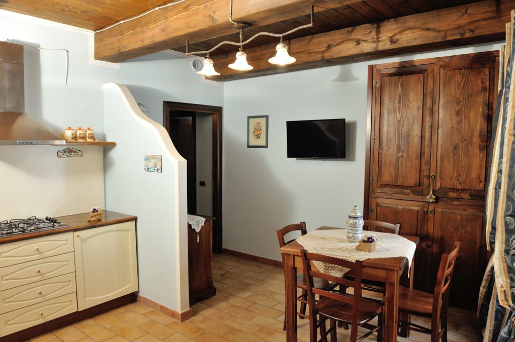 A kitchen with a stove, wooden cabinets, and a dining area with a table and chairs.