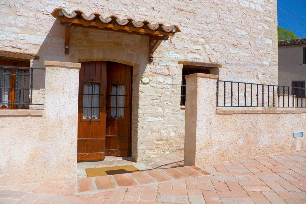 A stone building with a wooden door, a tiled roof, and a metal gate.
