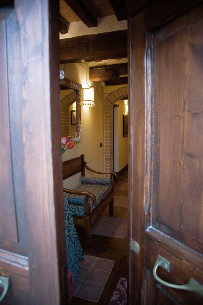 A wooden door leading to a bedroom with a bed, a mirror, and a staircase.