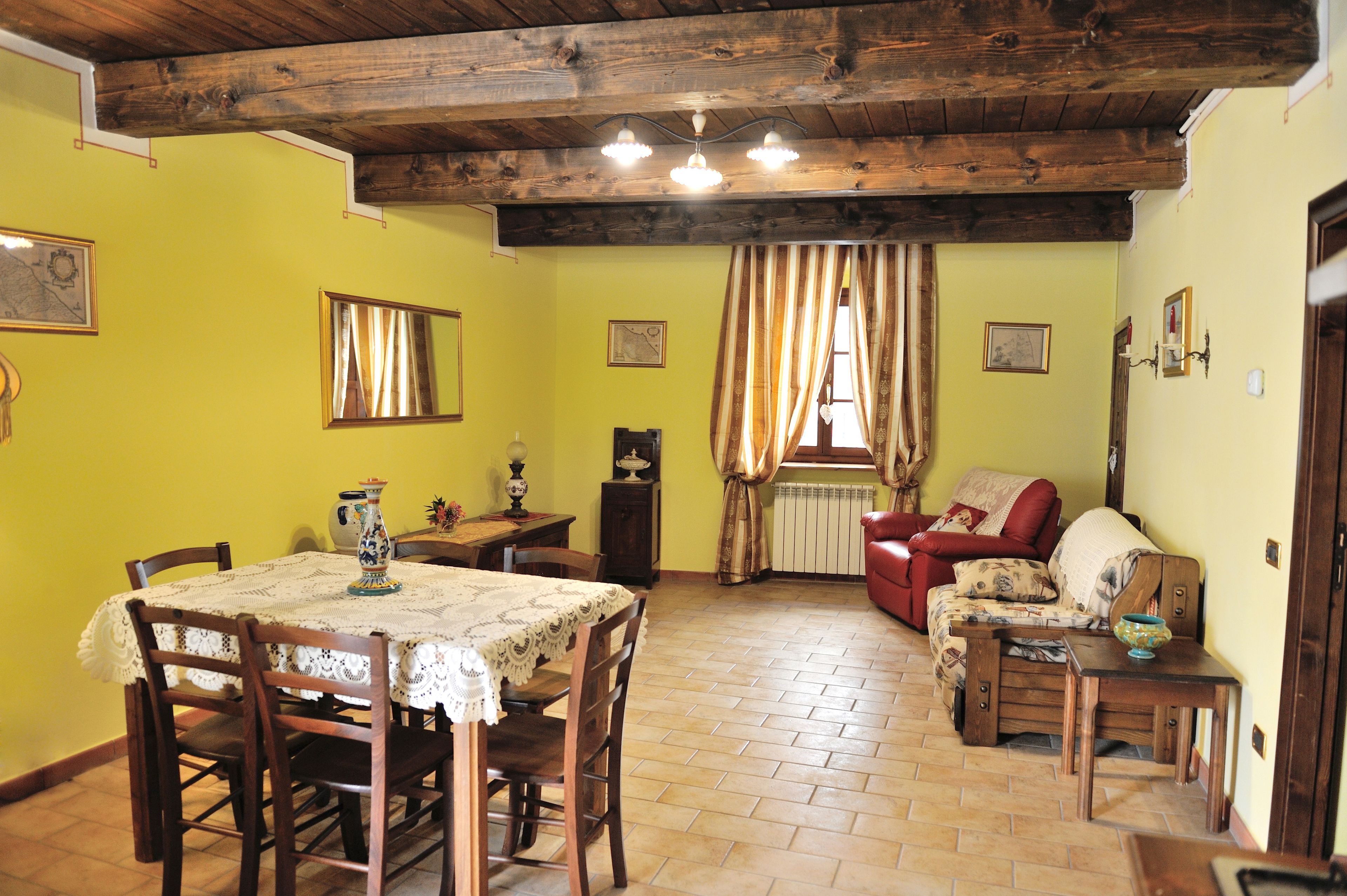 A dining area with a table set for four, wooden chairs, and a chandelier.