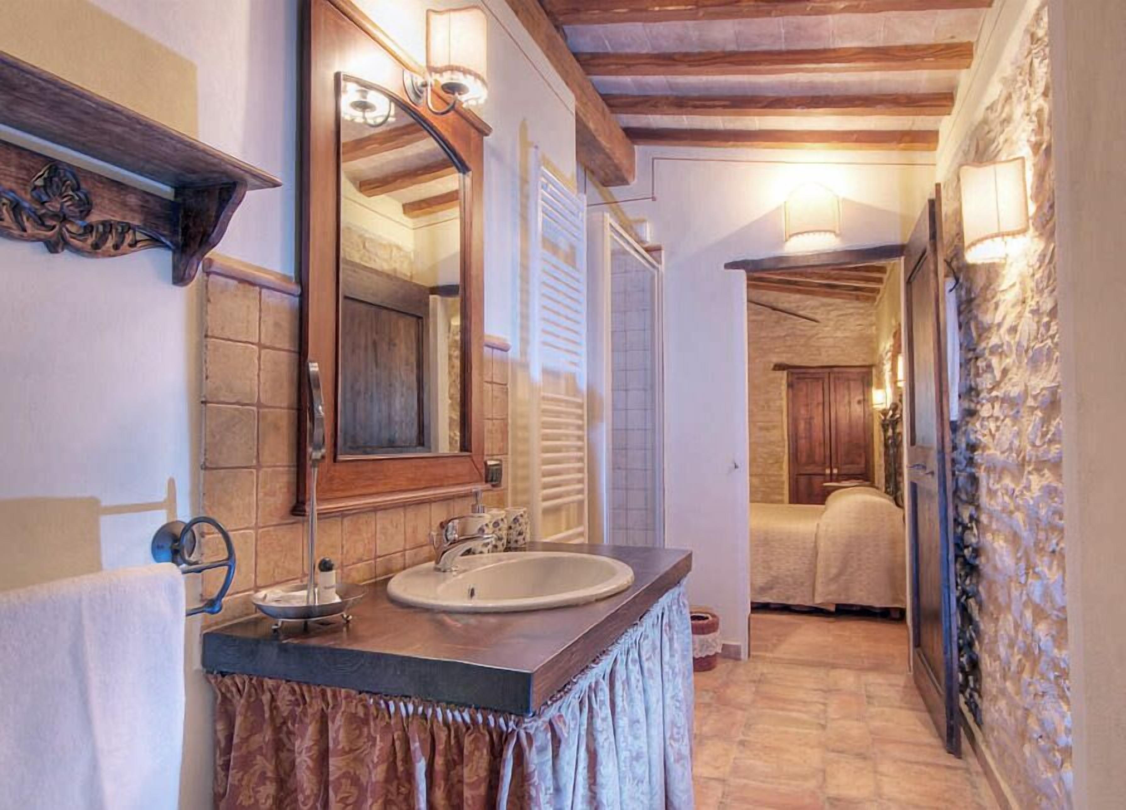 A bathroom with a wooden vanity, a large mirror, and a stone wall.