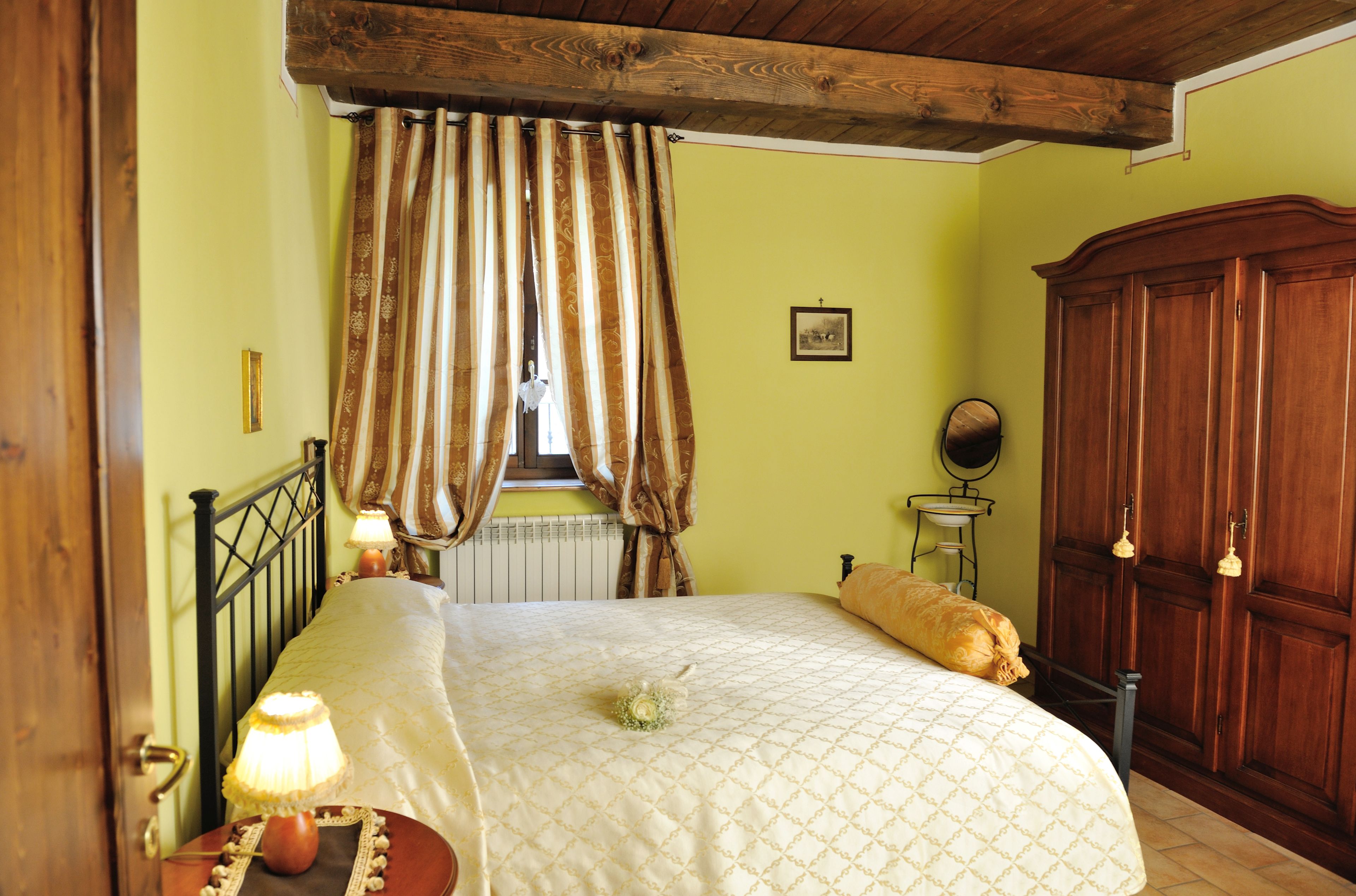 Une chambre à coucher comprenant un lit, une armoire en bois, une table de chevet avec une lampe et une fenêtre avec des rideaux.