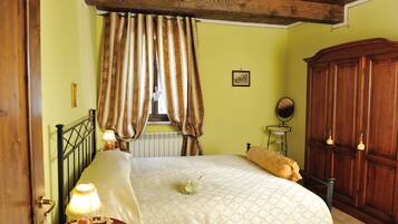Une chambre à coucher comprenant un lit, une armoire en bois, une table de chevet avec une lampe et une fenêtre avec des rideaux.