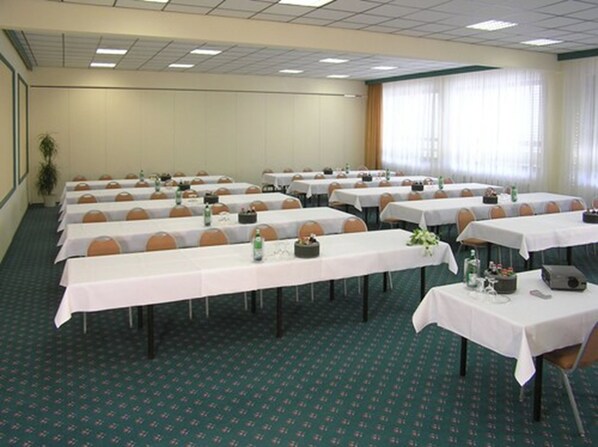 A conference room with multiple tables, chairs, and a carpeted floor.