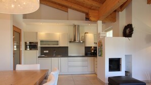 A modern kitchen with white cabinets, stainless steel appliances, and a wooden ceiling. - AvenidA Residenz Burg by Alpin Rentals (Kaprun)