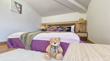 Cozy bedroom with a neatly made bed, bedside lamp, and plush teddy bear.