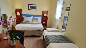 A hotel room with a double bed, a single bed, a desk with a chair, a small table with a plant, two bedside lamps, a framed picture on the wall, and a mirror on the wall. - L'Estuaire (Saint-Brevin-les-Pins)