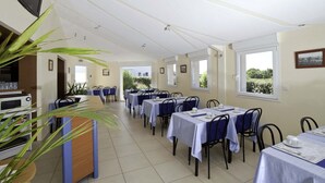 A dining area with multiple tables, chairs, and a counter with a microwave. - L'Estuaire (Saint-Brevin-les-Pins)