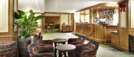 A bar area with patterned chairs, a large potted plant, and a bar counter with bottles.