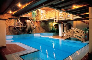 An indoor swimming pool with wooden architecture, a wooden bridge, and a view of the interior. - Hotel Club Relais Des Alpes (Madonna di Campiglio)