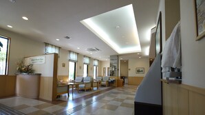 A hotel lobby with a checkered floor, seating area, and a reception desk. - Hotel Route-Inn Tokoname Ekimae (Tokoname)