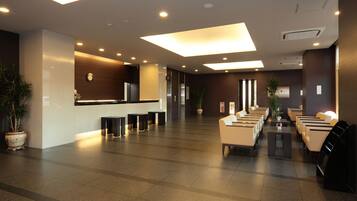 A spacious lobby with a reception desk, seating area, and potted plants.