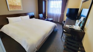 A hotel room with a large bed, a desk with a telephone, a chair, a small table, and a television. - Hotel Route - Inn Toyota Jinnaka (Toyota)