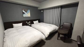 Ein Hotelzimmer mit zwei Betten, einem Sessel, einem Nachttisch mit Telefon und einem Bild an der Wand.