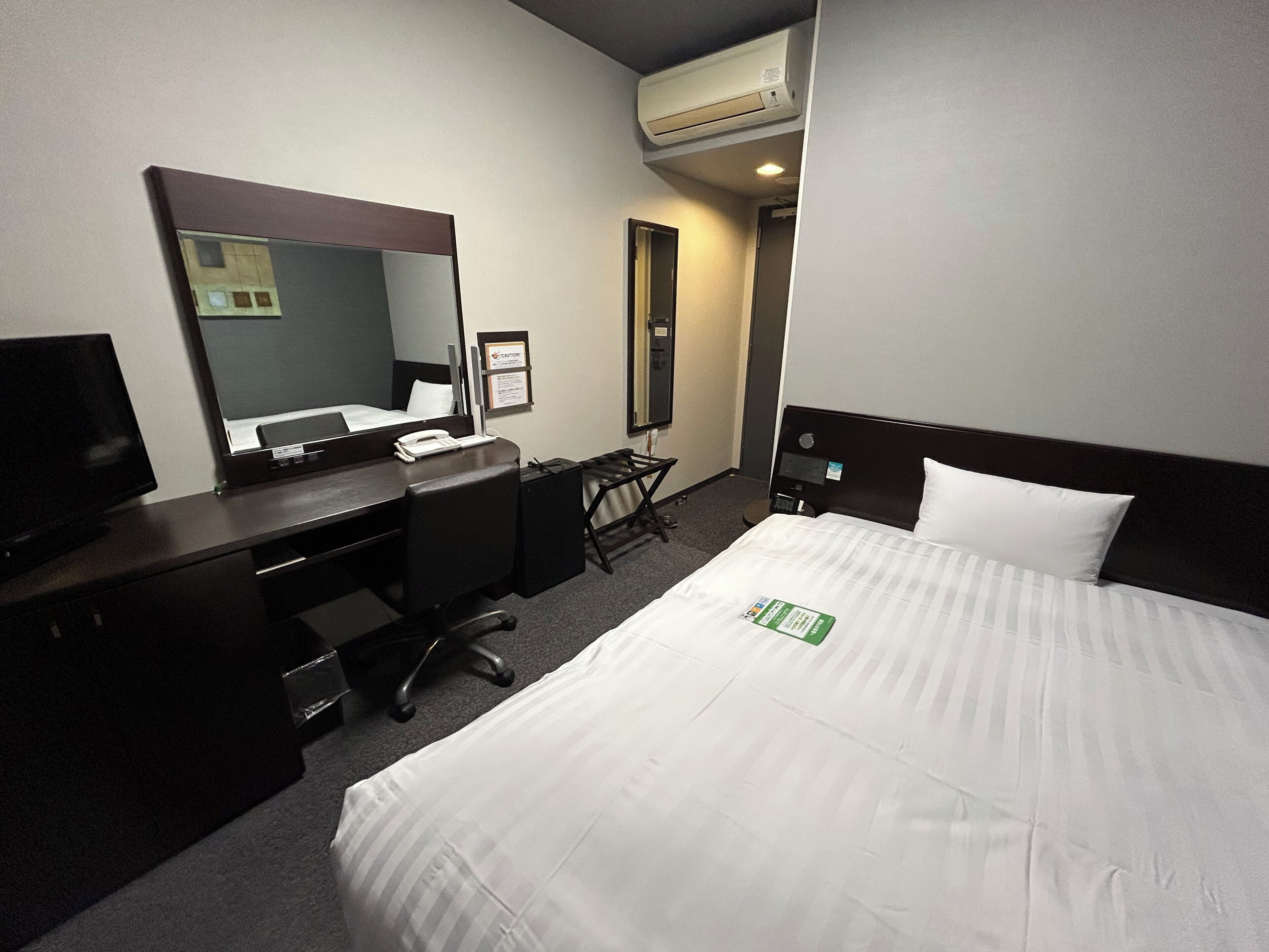 Una habitación de hotel con cama, escritorio, silla y televisor.