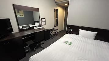 Una habitación de hotel con cama, escritorio, silla y televisor.