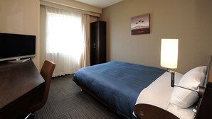 Ein Hotelzimmer mit Bett, Schreibtisch, Stuhl, Fernseher, Lampe und einem Bild an der Wand.