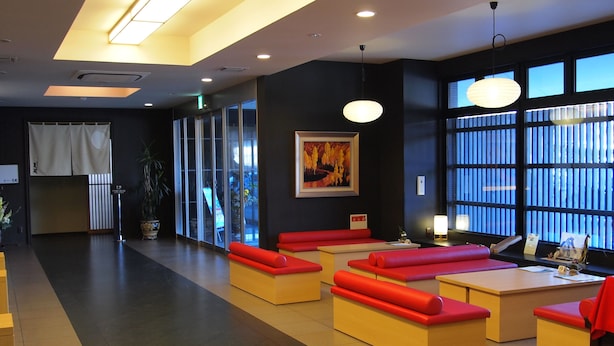 Eine moderne Lobby mit Sitzgelegenheiten, darunter rote und beigefarbene Sofas, einem großen Fenster mit Aussicht und einem Gemälde an der Wand.