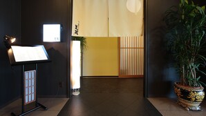 Ein Empfangsbereich mit Notenständer, Blumentopf und traditioneller japanischer Schiebetür.