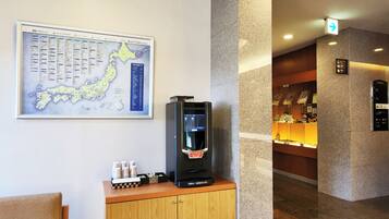 A hotel lobby with a map, a coffee machine, a wooden cabinet, and a reception desk.