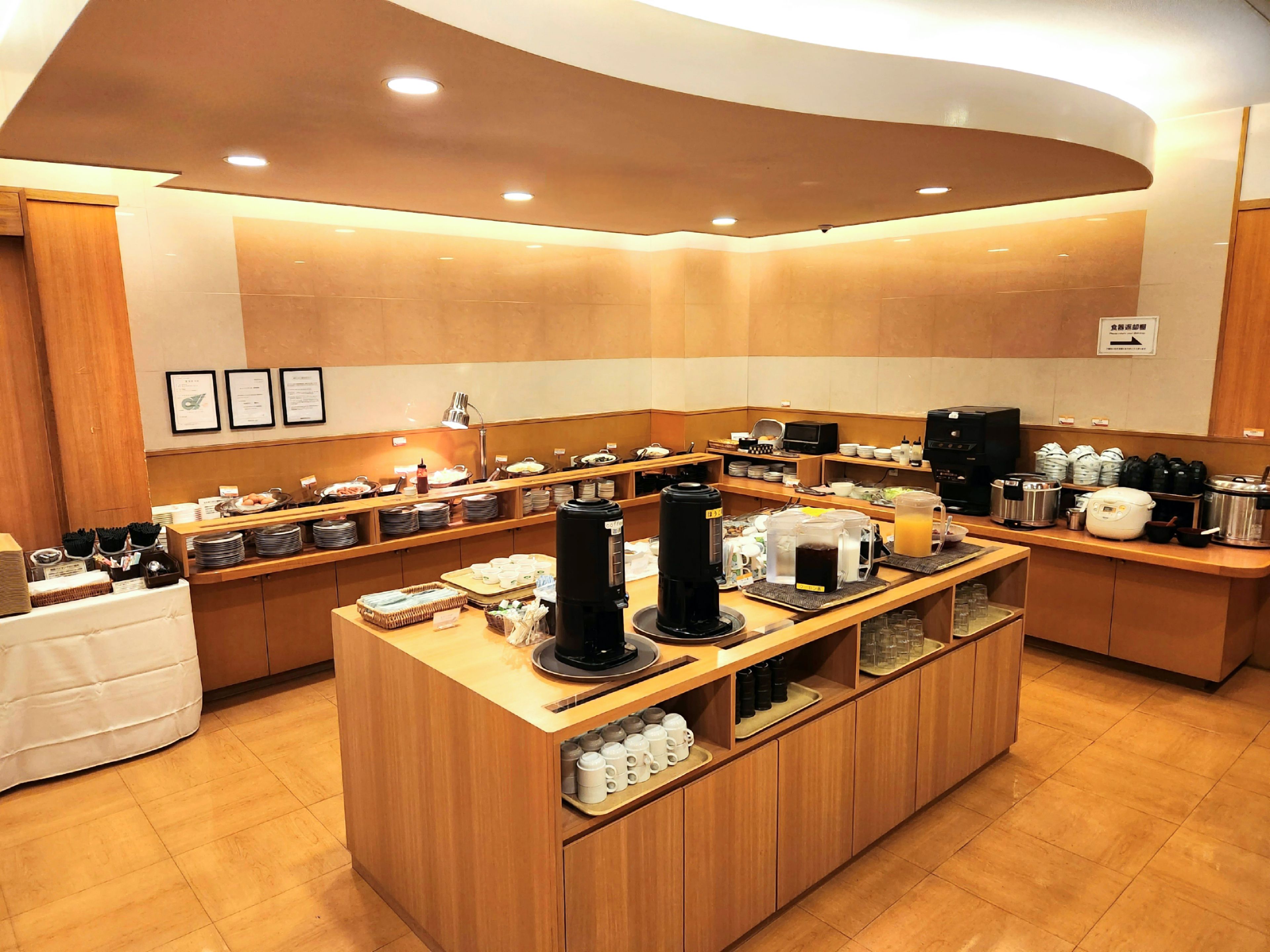 A modern breakfast buffet with various food items and coffee machines.