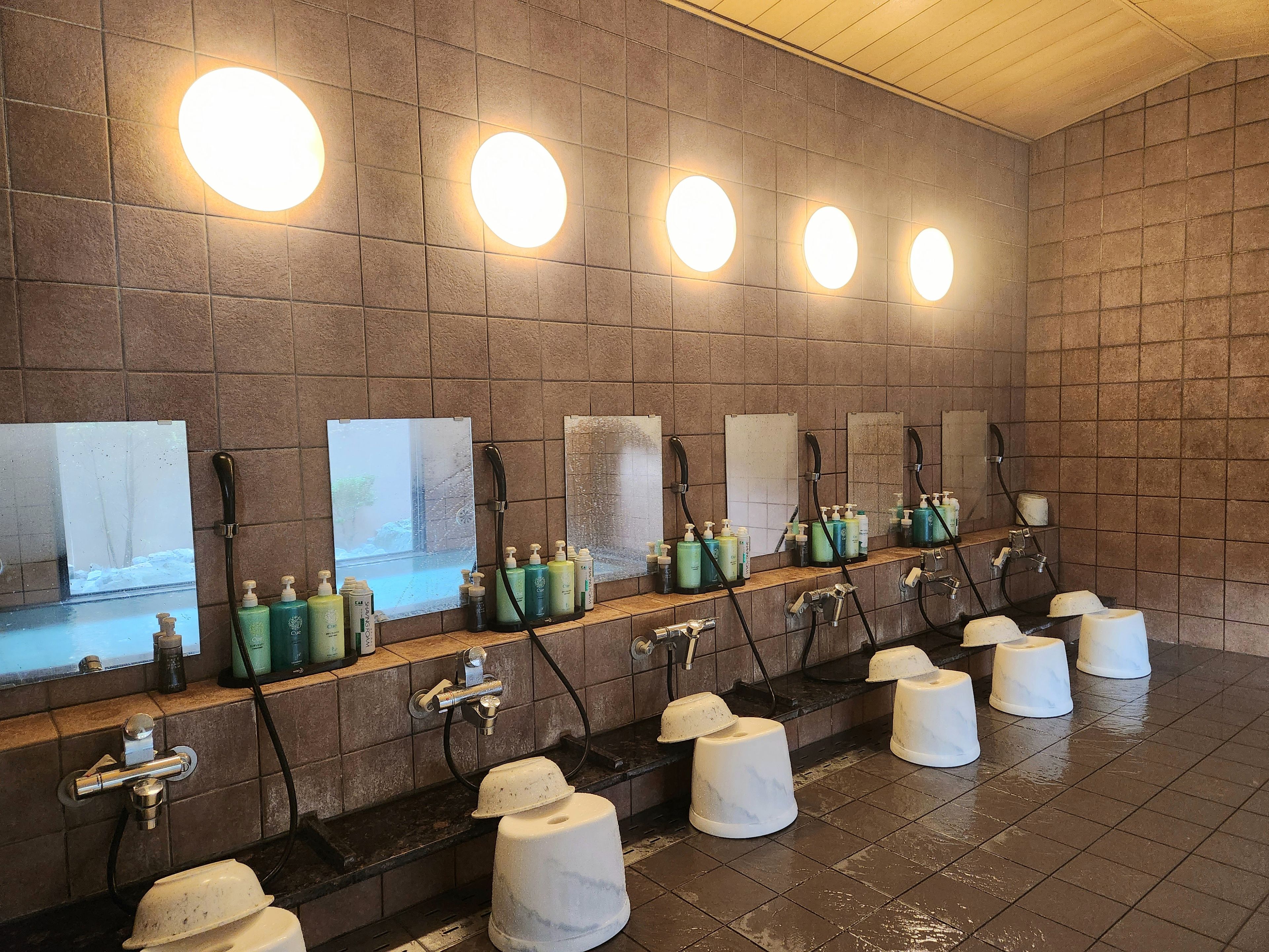 A public restroom with multiple sinks, hand soap dispensers, and paper towel holders.