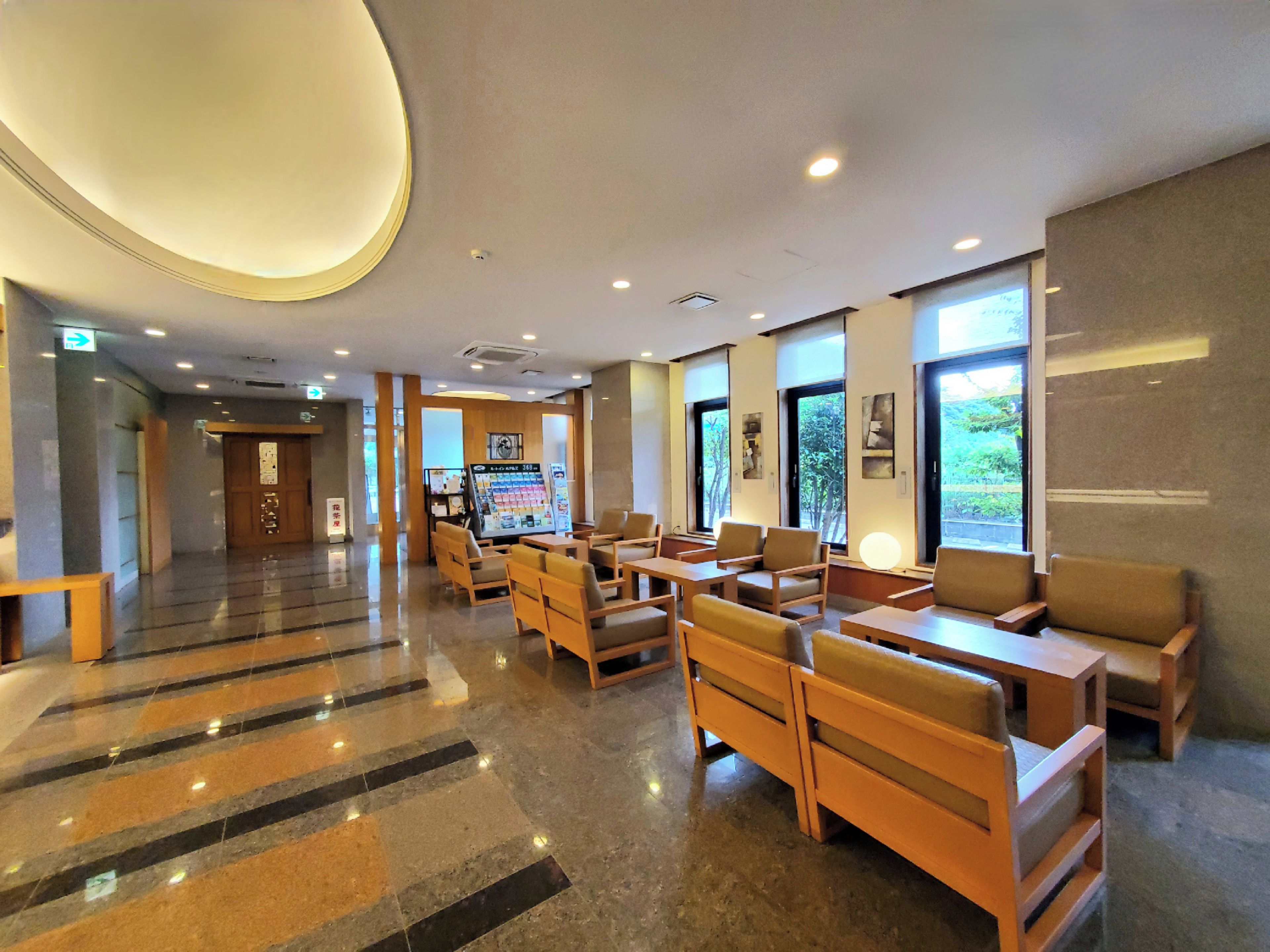 A hotel lobby with a reception desk, seating area, and large windows.