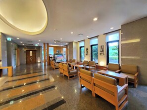 Un hall d’hôtel comprenant un comptoir d’accueil, un espace salon et de grandes fenêtres.