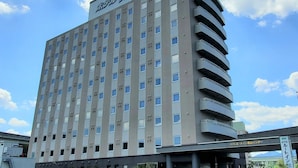 A multi-story hotel with a flat facade, numerous windows, and a curved balcony on the right side. - Hotel Route-Inn Kameyama Inter (Kameyama)