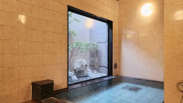A spa room with a large window, a stone bench, and a tiled floor.