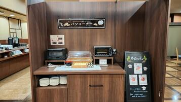 A self-service coffee station with a sign, a toaster, a microwave, and a menu board.
