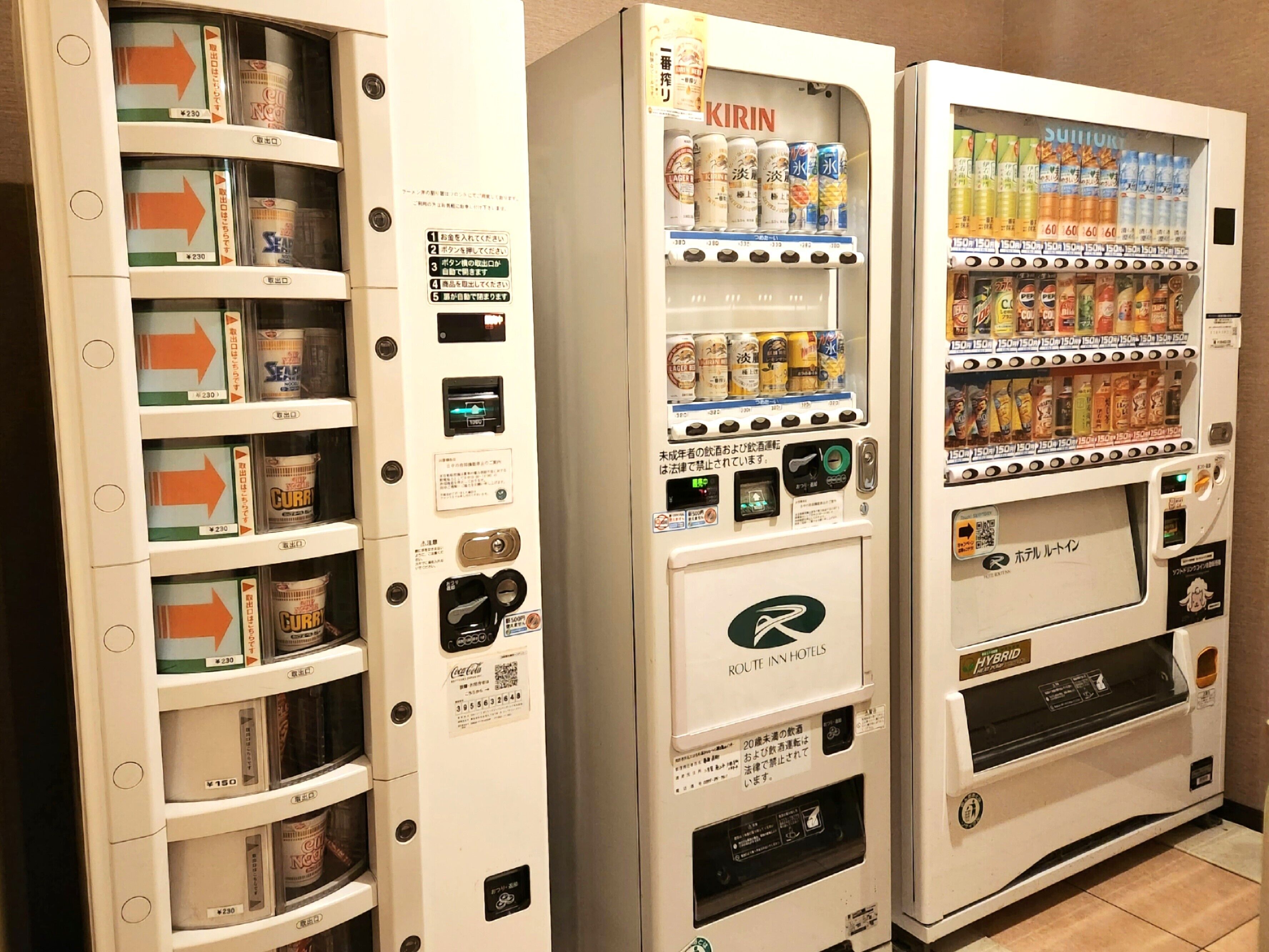 Automat mit Getränken und Snacks, ein QR-Code und das Logo der Route Inn Hotels.