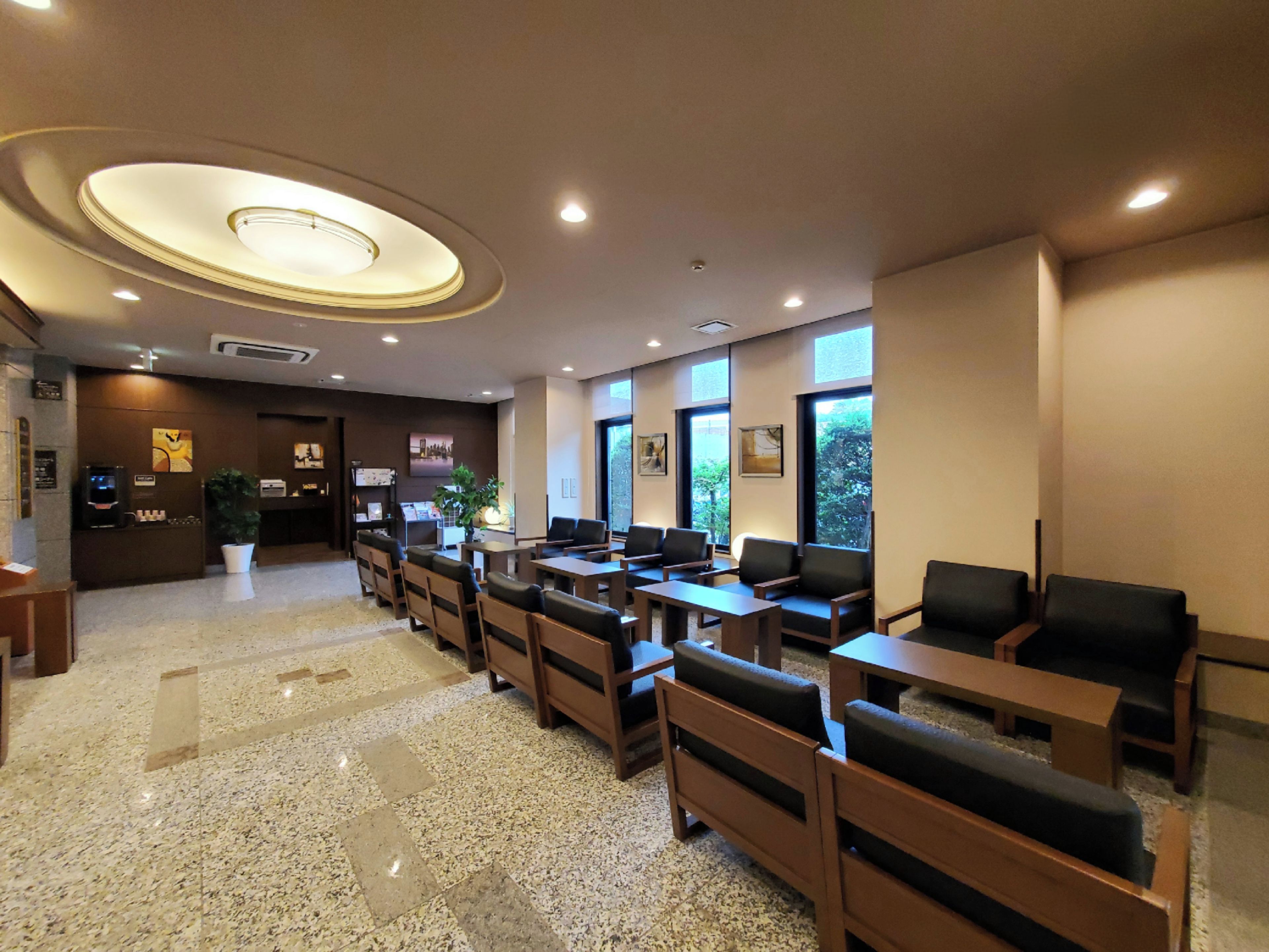A hotel lobby with a reception desk, seating area, and large windows.