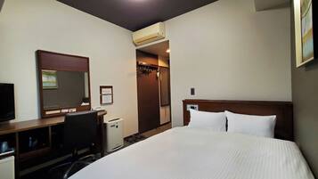 A hotel room with a bed, a desk, a chair, a television, an air conditioning unit, and a mirror.