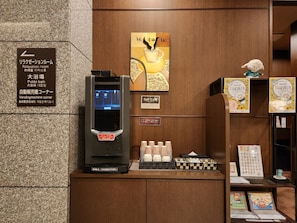 Una macchina per bevande, un manifesto di un caffè e un cartello per una sala relax.