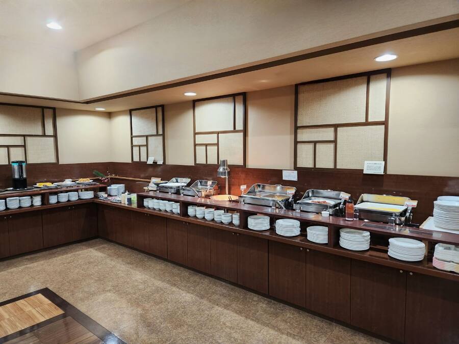 Montaje tipo bufé con múltiples estaciones de servicio, una máquina de café y una variedad de platos.