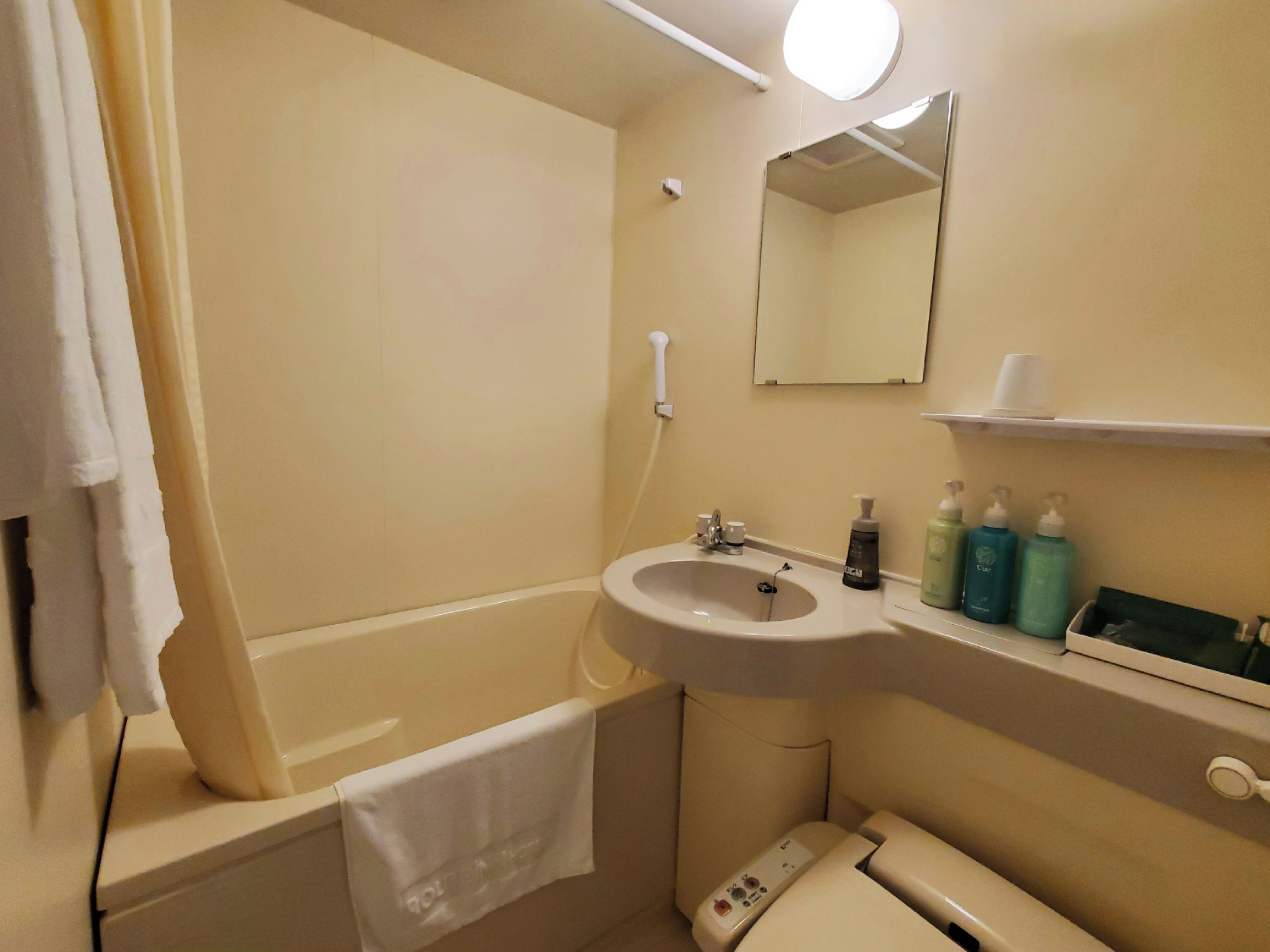 Et badeværelse med badekar, vask, toilet og spejl.