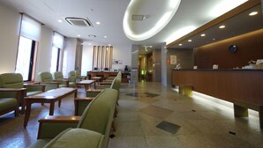 A hotel lobby with a reception desk, seating area with tables and chairs, and a large illuminated ceiling feature. - Hotel Route Inn Matsusaka Ekihigashi (Matsusaka)