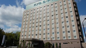 A multi-story hotel with a modern design, featuring a prominent entrance and a clear sky in the background. - Hotel Route Inn Nabari (Nabari)