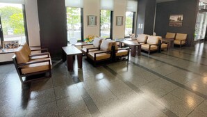 A spacious lobby with a modern design, featuring a seating area with sofas and chairs, a reception desk, and large windows providing natural light. - Hotel Route Inn Nabari (Nabari)