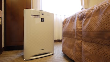 Een kamer met een witte airconditioner, een bed met een bedovertrek met patroon en een houten deur.