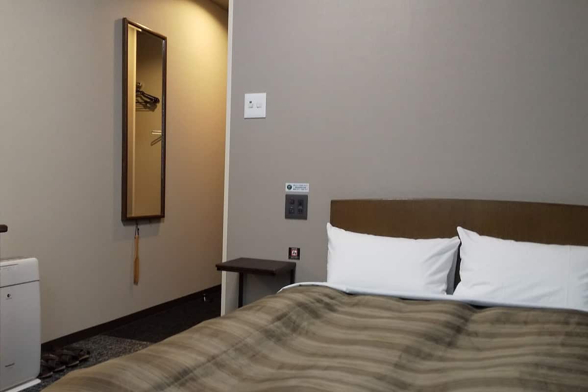 Ein Hotelzimmer mit Bett, Nachttisch, Spiegel und einer Steckdose.