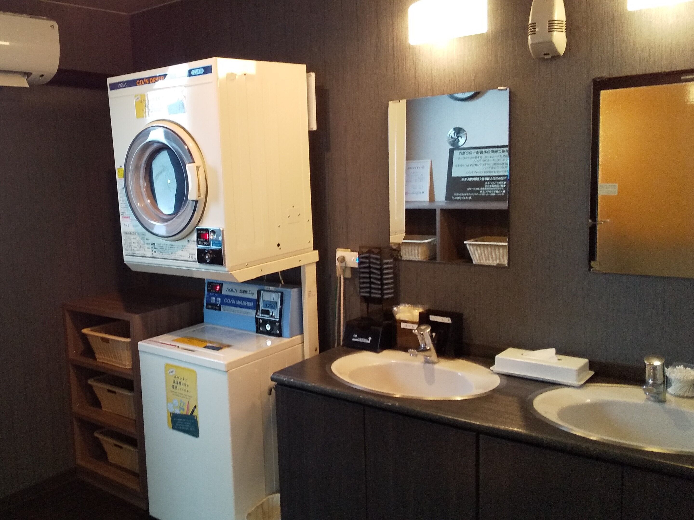 Un baño de hotel con lavadora, lavamanos y espejo.