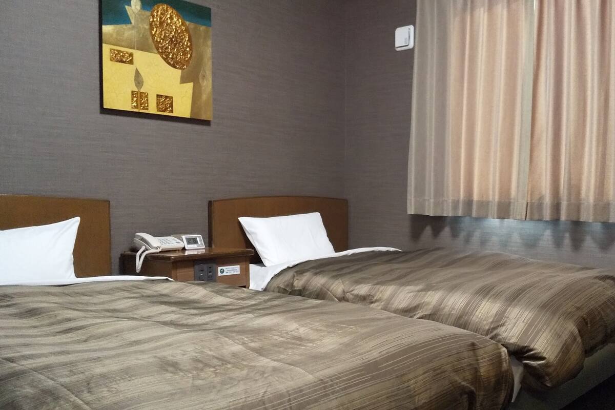 Ein Hotelzimmer mit zwei Betten, einem Nachttisch mit Telefon und einem Bild an der Wand.